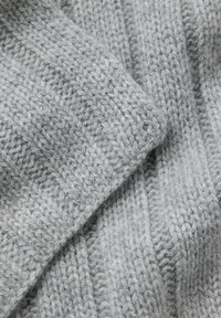 Szara dzianina o fakturowanym, prążkowanym wzorze. Gruba przędza tworzy przytulny wygląd z miękkimi, puszystymi włóknami widocznymi w splocie.