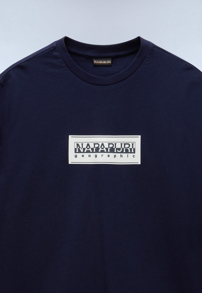 T-shirt in cotone blu navy con colletto a girocollo, caratterizzato da una grafica rettangolare bianca che include il testo "NAPAPURI" e "geographic".