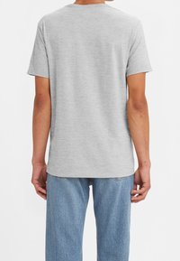 T-shirt en coton gris avec une coupe décontractée, des manches courtes et un col rond classique. Texture de tissu lisse remarquable et design simple.