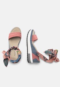 Sandales à plateforme roses et en denim avec des brides en tissu à fleurs. Texture lisse, bout ouvert et semelle en caoutchouc avec une accent noir et une semelle intermédiaire blanche.