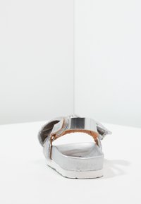 Srebrne sandały z teksturowaną cholewką, regulowanym paskiem z klamrą i kontrastującą korkową wkładką na białej podeszwie.