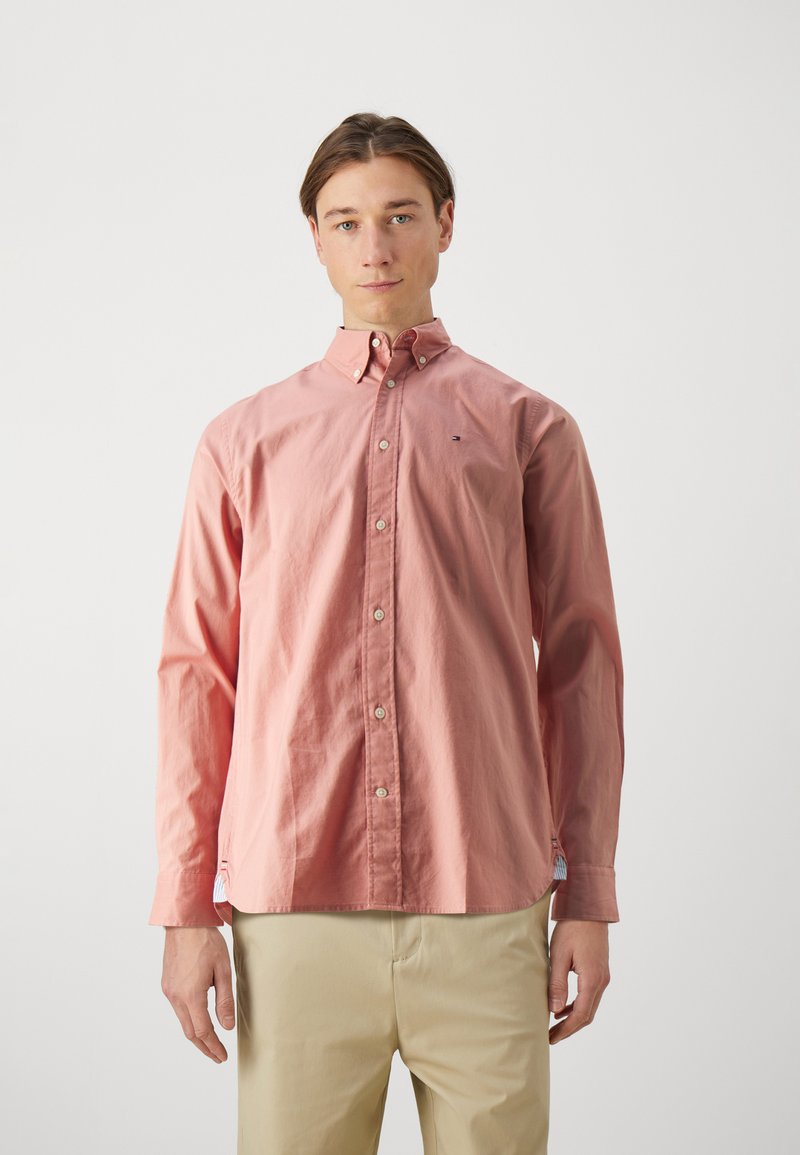 Camicia button-up rosa chiaro con maniche lunghe, colletto standard e un piccolo logo sul petto. Tessuto morbido e design a vestibilità rilassata.