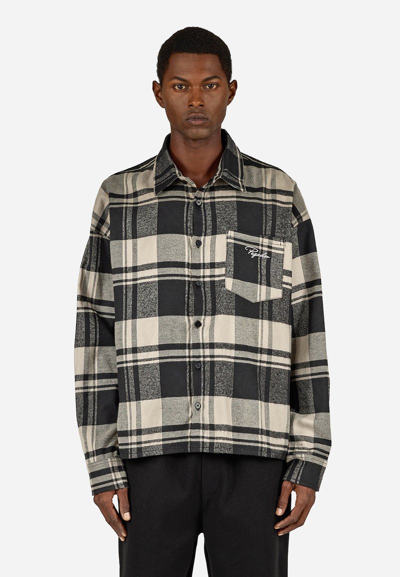 Fekete és bézs kockás ing, gombos kialakítással, hosszú ujjakkal, elülső zseb brokáddal, puha anyagból készült.