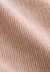 Bomuldsstof med en blød tekstur, der har tynde hvide og røde lodrette striber på en lys cremefarvet baggrund. Subtle vævning kan ses.