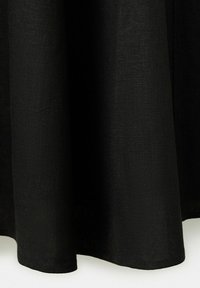 Čierna látková záclona s viditeľnou textúrou a jemnými záhybmi, visiaca rovno dole na svetlom pozadí.