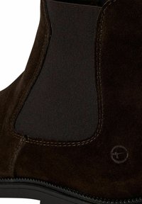 Bottines en suede marron avec panneaux latéraux élastiques, tissu texturé et couture contrastée ; ornées d'un logo circulaire près de la base.