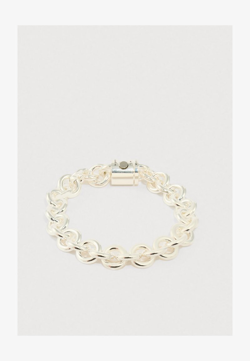 Sudraba ķēdes rokassprādze ar savienotām apaļām un ovāla formas saitēm, plakanu virsmu un cilindrisku aizdari. Gluda, spīdīga apdare.