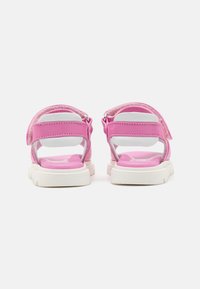 Růžové sandály se syntetickým svrškem, bílými polstrovanými podrážkami, nastavitelnými popruhy a texturovanou zadní částí pro pohodlí a dobrý grip.