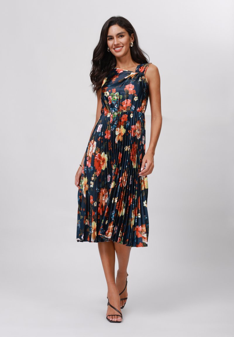 Rochie plisată florală cu un fond albastru închis, având flori vibrante de culoare roșie, galbenă și albă. Design cu un umăr, material ușor, lungime până la genunchi.