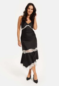 Black satin dress with lace trim, featuring a fitted bodice, V-neck, and flared hemline. Paired with black high-heeled shoes.