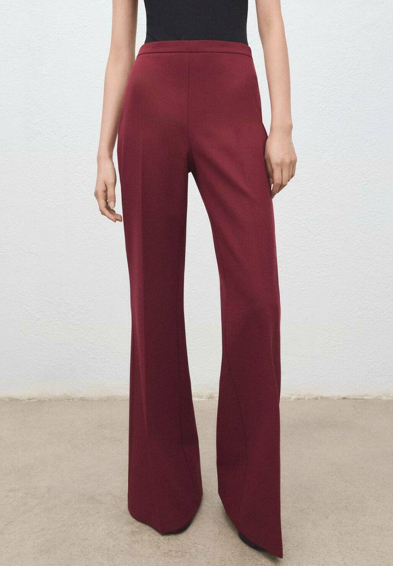 Pantalon large bordeaux en tissu lisse, avec une coupe ajustée, une taille haute et des coutures nettes. Détail texturé sur les côtés.