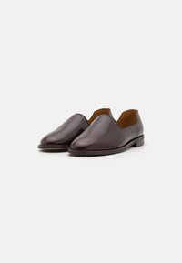 Brune skinn slip-on sko med en jevn finish, mandelformet tå, lav hæl og åpne sider, med en kontrasterende beige interiør.