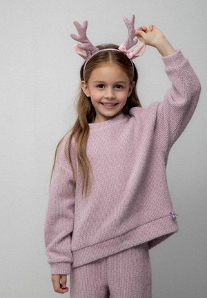 Różowy dzianinowy sweter o luźnym kroju i teksturowanym wykończeniu, zestawiony z pasującymi różowymi dzianinowymi spodniami. Zawiera opaskę na głowę z rogami z metalicznymi akcentami.