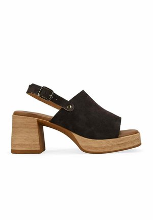 Sandalia negra de ante con puntera abierta, tacón de bloque de madera y correa ajustable en el tobillo con hebilla metálica.