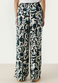 Wide-leg pants in a floral pattern, featuring blue and navy on a cream background. Elastic waistband and smooth fabric texture.