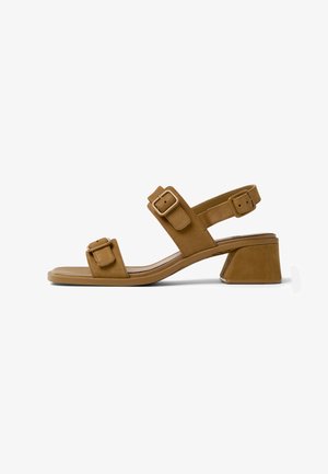 Sandale en cuir marron avec deux boucles réglables, design à bout ouvert et petit talon bloc. Style minimaliste avec texture lisse.