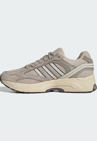 Beiger und grauer Mesh-Laufschuh mit Schnürverschluss, gepolsterter Sohle und drei reflektierenden Streifen an der Seite.