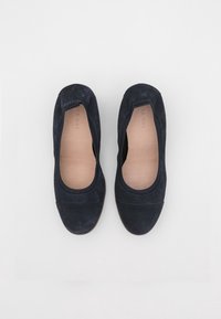 Námořnické modré sukně s kulatou špičkou a elastickými okraji, položené na bílém pozadí, které ukazují jejich jednoduchý a elegantní design.