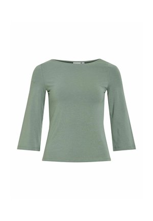 Zeleno, usko pristajuće žensko majica s rukavima tri četvrtine dužine i otvorenim okruglim izrezom na bijeloj pozadini.