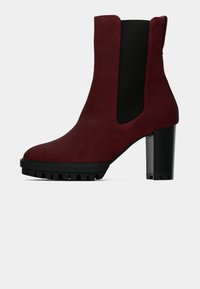 Stivale alla caviglia in suede bordeaux con pannelli laterali in elastico neri, punta arrotondata e tacco chunky nero con suola a carrarmato per una migliore aderenza.