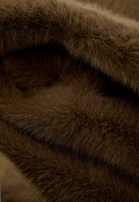 Bruine imitatiefantstof met een zachte, pluizige textuur en wisselende plooienhoogtes, met een rijke, egale kleur en een soepele val.