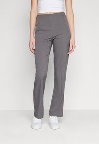 Szare formalne spodnie o prostym kroju, wykonane z tkaniny o delikatnej strukturze. Połączone z białymi sneakersami dla uzyskania casualowego wyglądu.