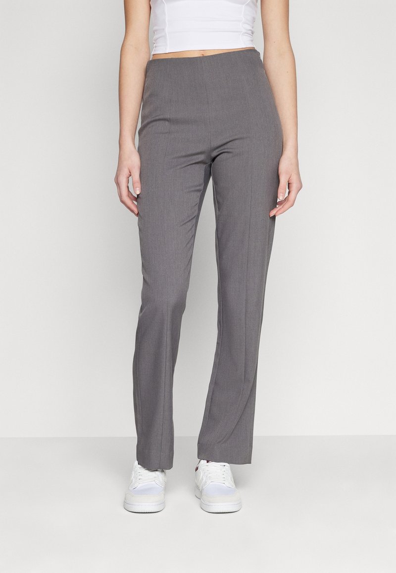 Szare formalne spodnie o prostym kroju, wykonane z tkaniny o delikatnej strukturze. Połączone z białymi sneakersami dla uzyskania casualowego wyglądu.