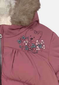 Rosa pink puffy jakke med en faux fur krave, der har en broderet bjørn og blomsterdesign i pink og teal på brystet.