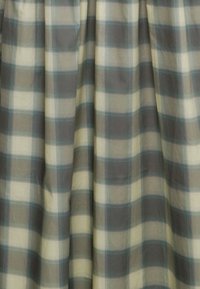 Vävt tyg med ett stort, beige och grått rutmönster, med ljusblå accenter, slät textur och enhetlig drapering.