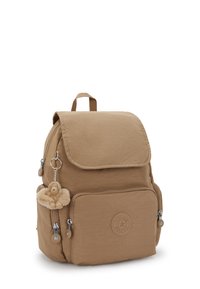 Hnědý nylonový batoh s klopovým uzávěrem, přední kapsou a stříbrnými kovovými doplňky. Obsahuje plyšového opičáka připevněného k zipu jako klíčenku.