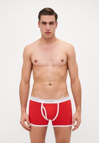 Boxers rouges avec ceinture blanche portant le logo 'DSQUARED2', coupe ajustée, tissu doux et détails de surpiqûre contrastante.