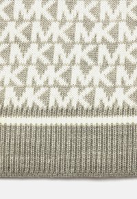 Szara i biała dziana tkanina z powtarzającymi się geometrycznymi wzorami krzyża oraz prążkowanym wykończeniem na dole.