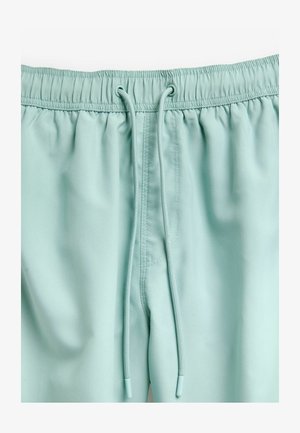 Világos menta zöld rövidnadrág puha anyagból, rugalmas derékrésszel, zsinórral és oldalsó zsebekkel. Sima textúra minimális varrásokkal.