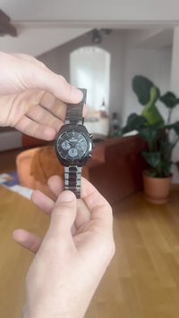 Musta roostevabast terasest kell ruudukujulise kellanäidiku ja kolme alamõõdikuga. Omab lingitud metallist rihma ja minimalistlikku disaini.