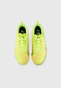 Baskets de sport jaune vif avec une tige texturée, dotées d'accents roses et noirs, de lacets standards et d'un design profil bas.