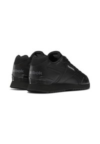 Czarne sportowe sneakersy z gładką skórzaną cholewką, teksturowanymi akcentami z siateczki i żłobioną gumową podeszwą. Zawierają logo Reebok po boku.