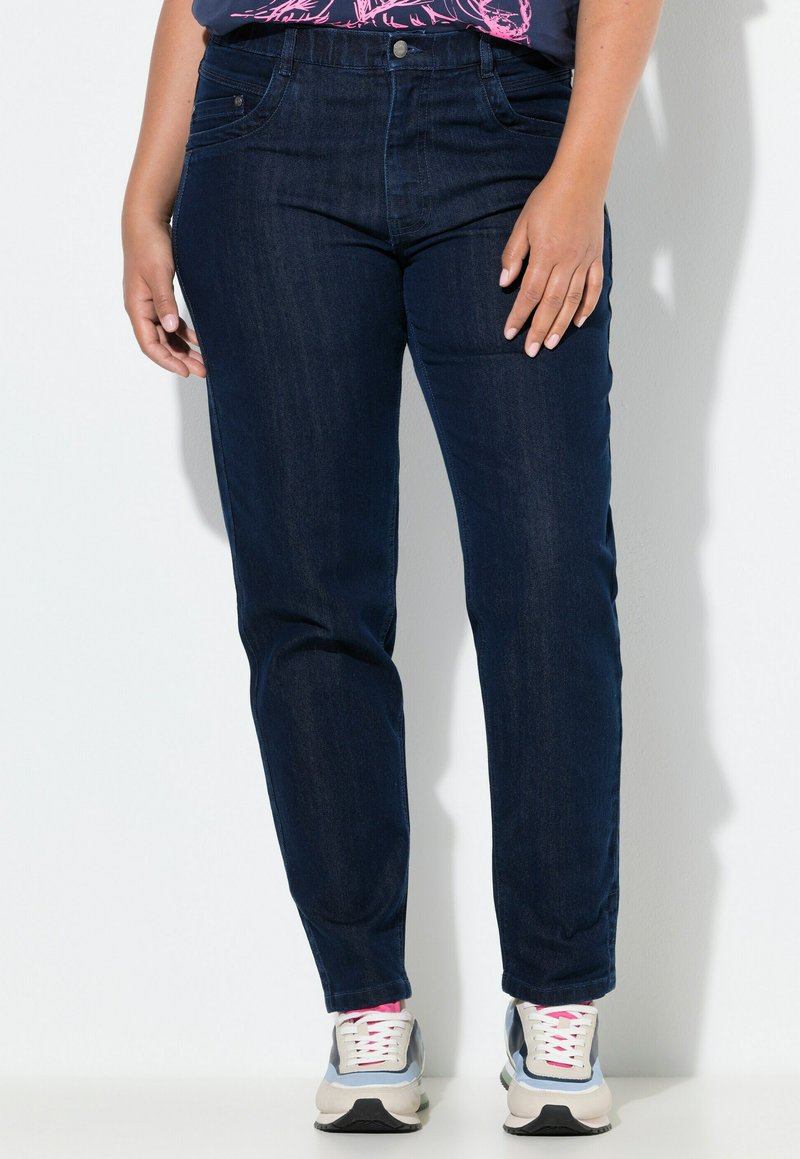 Tmavě modré džíny s úzkým střihem, stylizací s pěti kapsami a knoflíkovým zapínáním, doplněné šedými a bílými teniskami.
