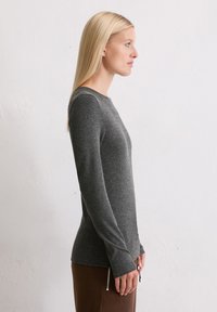 Długo-sleeve, dopasowana koszula w ciemnoszarym kolorze, wykonana z miękkiego materiału; posiada okrągły dekolt i wydłużone mankiety.