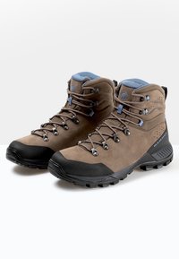 Scarpe da trekking marroni realizzate in pelle e materiali sintetici. Presentano una punta in gomma nera, accenti blu e occhielli metallici per i lacci.