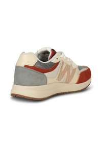 Sneaker z beżową siateczkową cholewką, szarymi zamszowymi akcentami i czerwonymi nakładkami. Podeszwa z amortyzacją i teksturowaną gumową powierzchnią zapewniającą przyczepność.