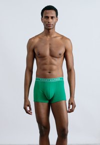 Zöld pamut boxer, testhez simuló fazonban, fehér derékkal, amelyen a "TOMMY HILFIGER" felirat látható. Sima tapintású, és nem tartalmaz látható mintákat.