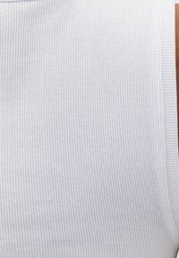 Tela blanca acanalada con finas rayas verticales y un borde cuidadosamente cosido en el lado derecho.