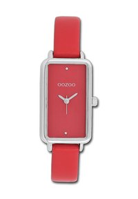 Montre rectangulaire rouge avec une finition mate, des accents en argent et un cadran simple. Dotée d'un bracelet en cuir rouge doux. Design classique et minimal.