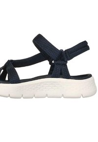 Sandale à bout ouvert avec des sangles en tissu bleu marine, dotée d'une épaisse semelle blanche texturée et d'une fermeture à glissière pour un ajustement personnalisable.