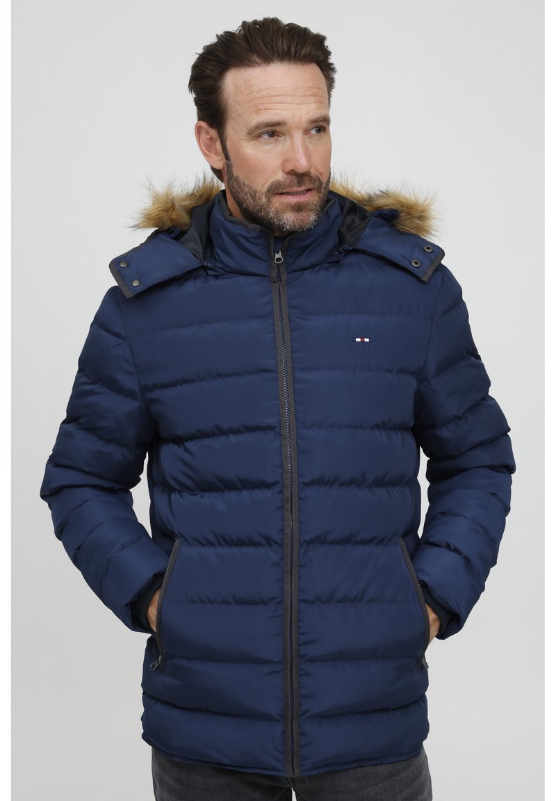 Mørkeblå puffjakke med hette foret med falsk pels, vertikal quilting, to frontlommer og glidelås foran.