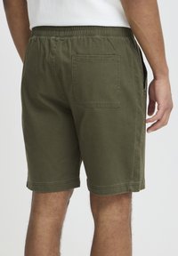 Vyriški alyvuogių žalios spalvos šortai iš medvilnės su elastinga juosmens juosta, šoniniais kišenėmis ir vienu užpakaliniu kišene. Standartinio kirpimo, vientisos tekstūros.