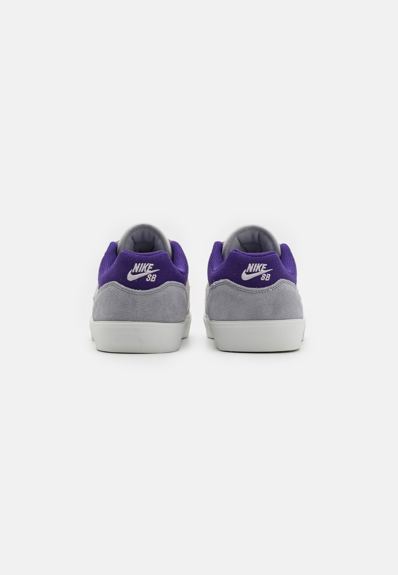 Lila und graue Nike SB Sneaker aus Wildleder und Mesh-Materialien, mit einer grauen Gummisohle und weißen Nike-Logo-Details an der Ferse.