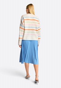 Strickpullover mit pastellfarbenen Streifen in Rosa, Grün und Orange; kombiniert mit einem plissierten blauen Rock und grauen Absatzsandalen.