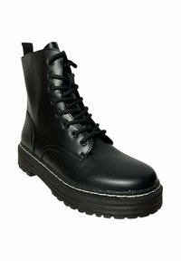 Botín negro de cuero hasta el tobillo con suela plana, diseño decordones y detalles de costura. Cuenta con una lengüeta y punta redondeada.