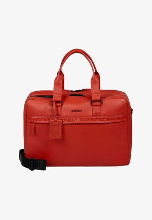 Rote Leder-Reisetasche mit doppelten Griffen, verstellbarem Schultergurt, geprägtem Markennamen und einem Anhänger mit einem Bärenemblem.